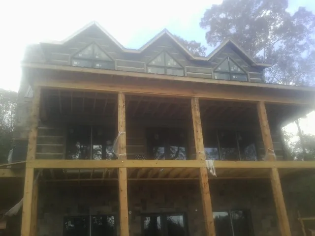 Dormers and porch framing on a large log home under construction — Roof Coating work by our crew in Pryor