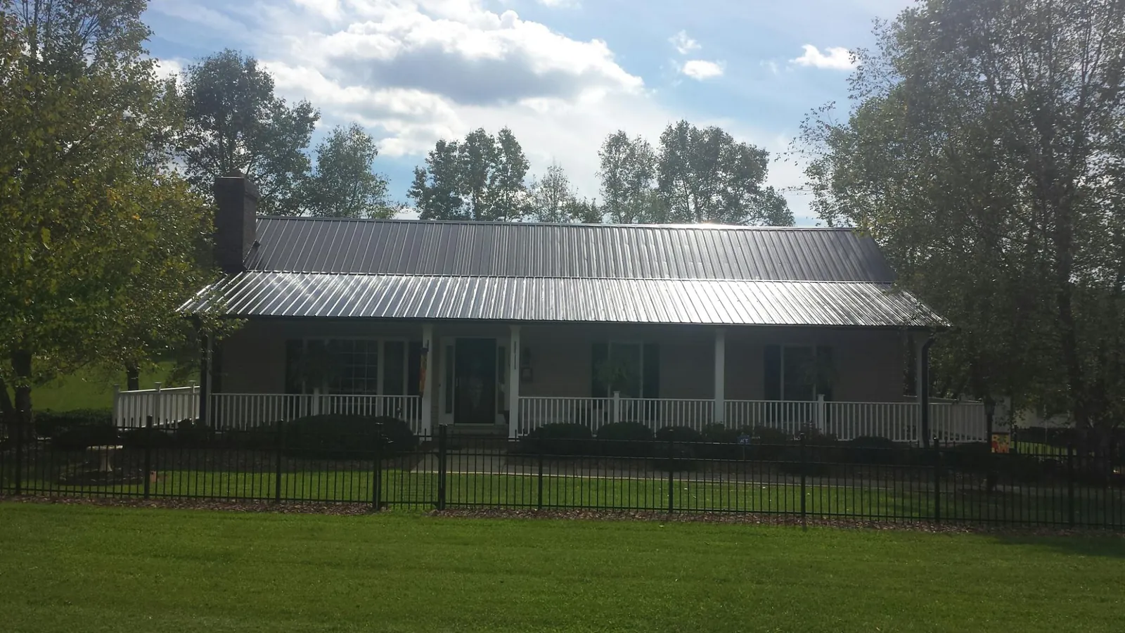 Gray metal roof on a brick ranch with a full width front porch — Gutter Guard Installation work by our crew in Pryor