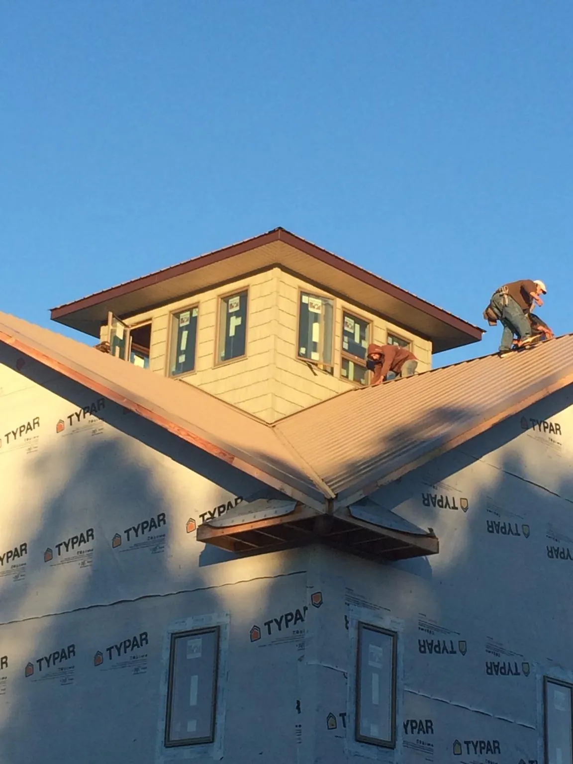 Roofers working around a rooftop cupola on a new metal roof at sunset — Roof Waterproofing in Pryor by Roofing Brothers